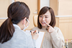歯科医師に歯を見せながら相談する女性患者
