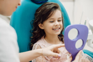 歯科医師が持つ鏡で自分の歯を確認する少女