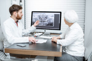 歯科医から歯のレントゲン写真で説明を受ける高齢女性