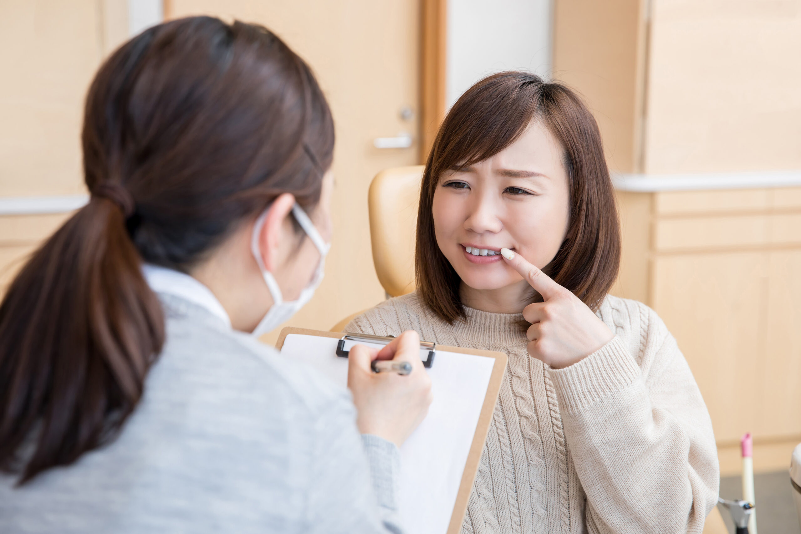 歯科医師に歯を見せながら相談する女性患者
