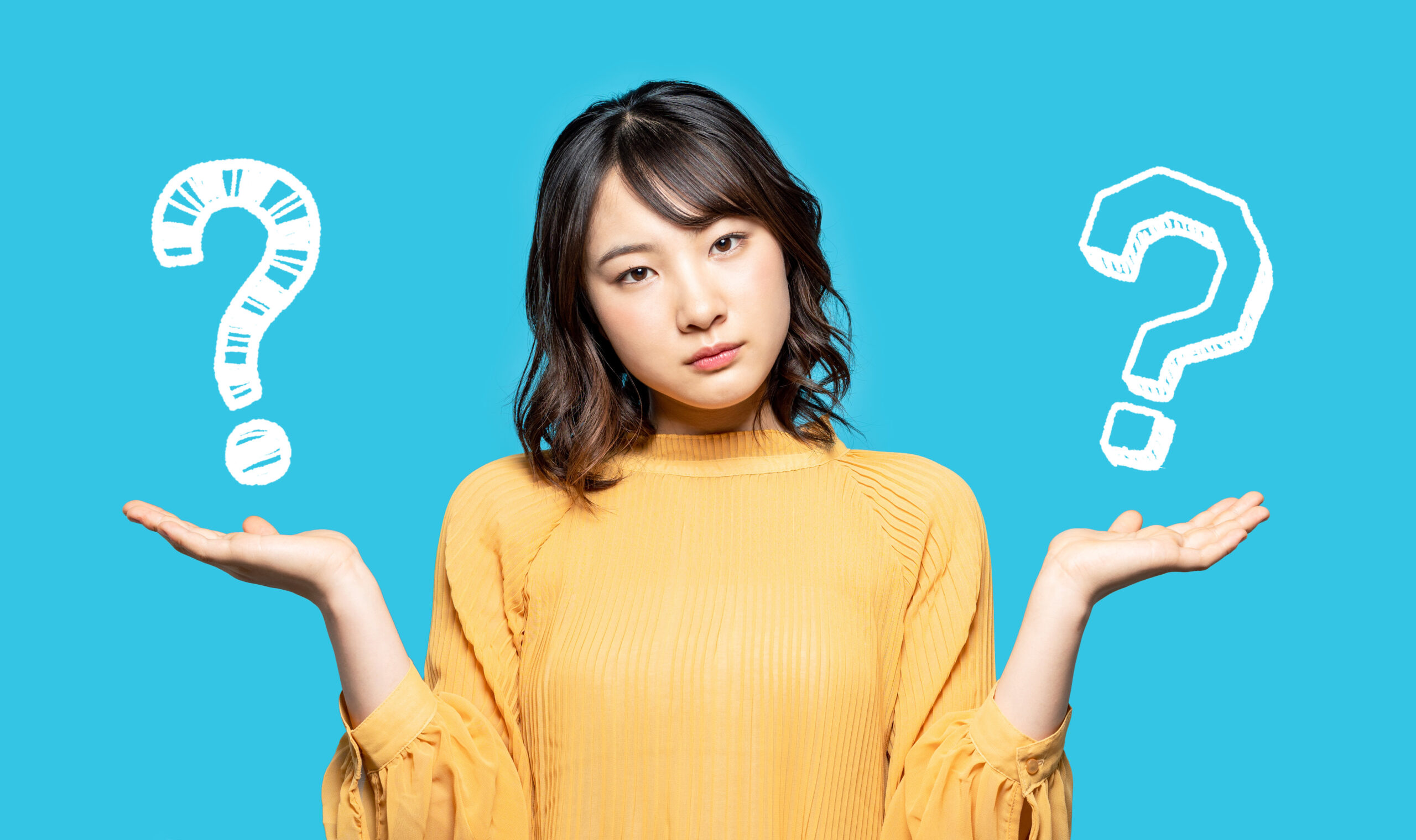 青い背景の前で?を比較する女性