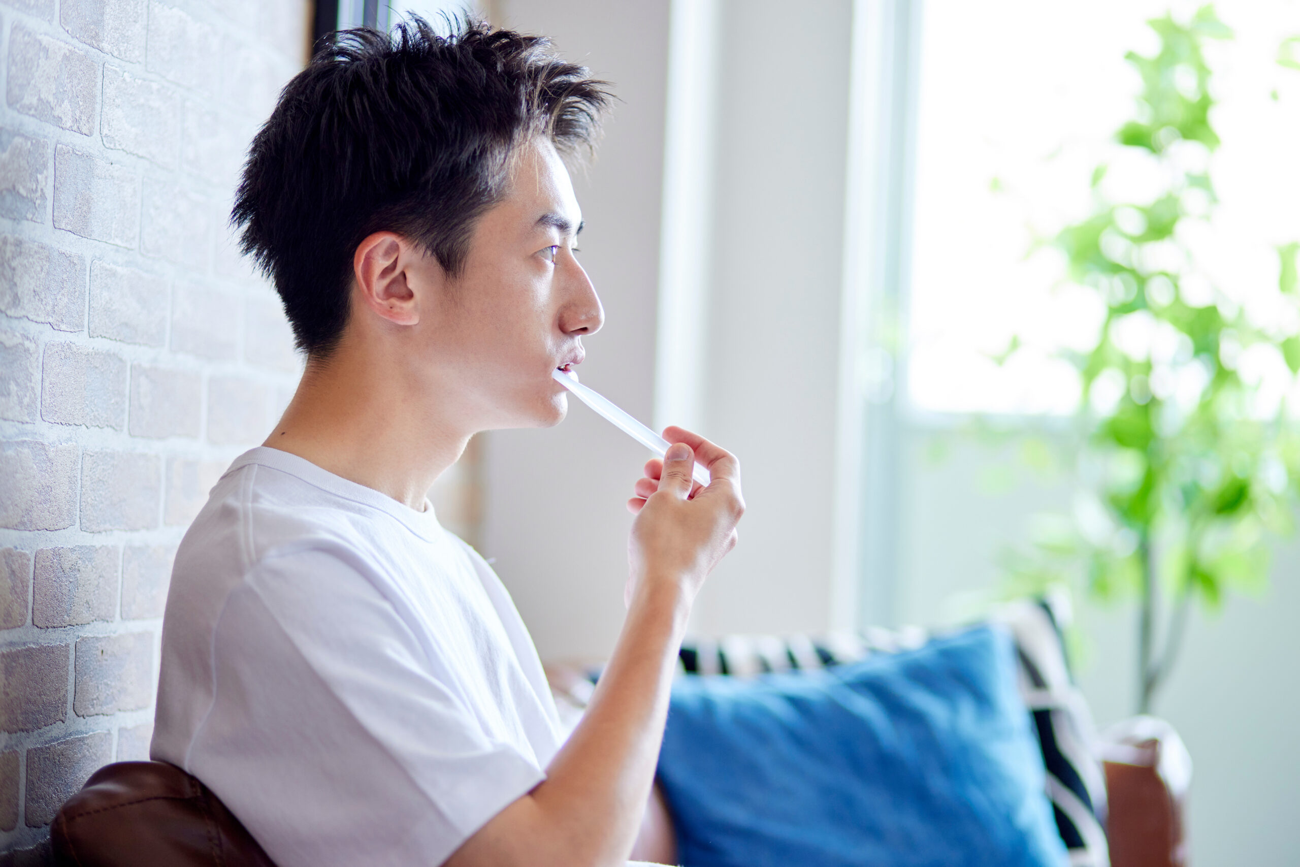 ソファに座って歯磨きをする若い日本人男性